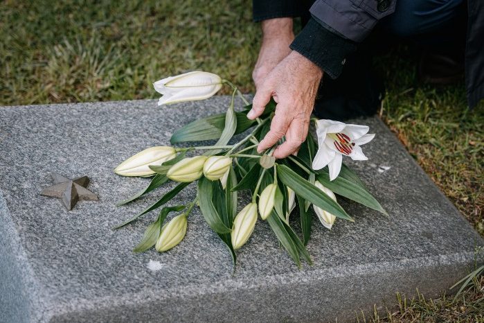 Flores de despedida por un fallecimiento Ramo de lirios blancos sobre una lápida: vaciado por defunción en Madrid