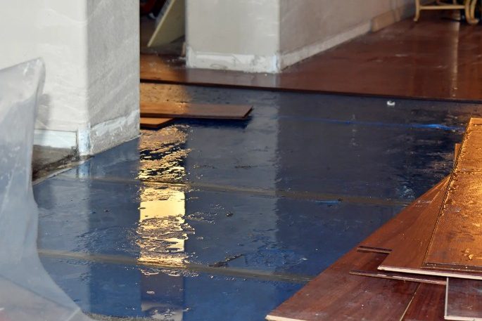 Tarima levantada por una filtración de agua Suelo encharcado y lamas levantadas en un sótano con humedad de Leganés