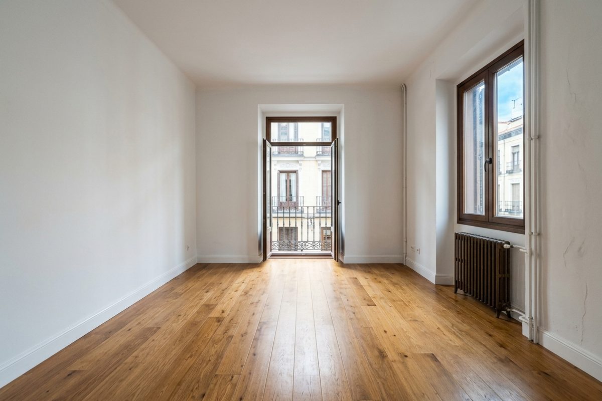 Salón después del vaciado Salón vacío con tarima y balcón tras el vaciado de un piso en Madrid
